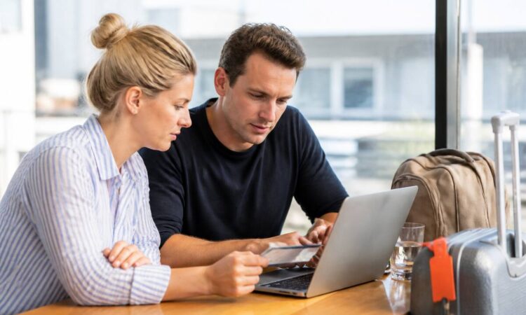 Koppel met laptop en reisnotities die vakantie-aanbiedingen vergelijken op een rustig moment
